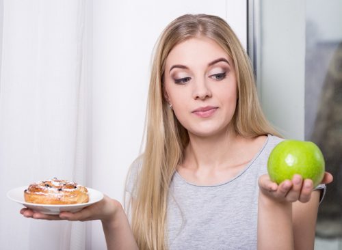 Mujer que elige manzanas en lugar de pastel de azúcar: pérdida de peso poco saludable