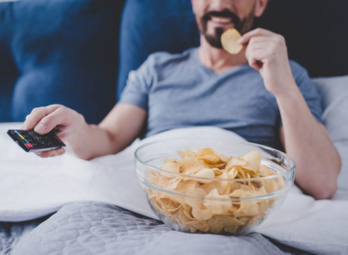 30 consejos efectivos para perder peso que debe probar El hombre mira la televisión y come papas fritas