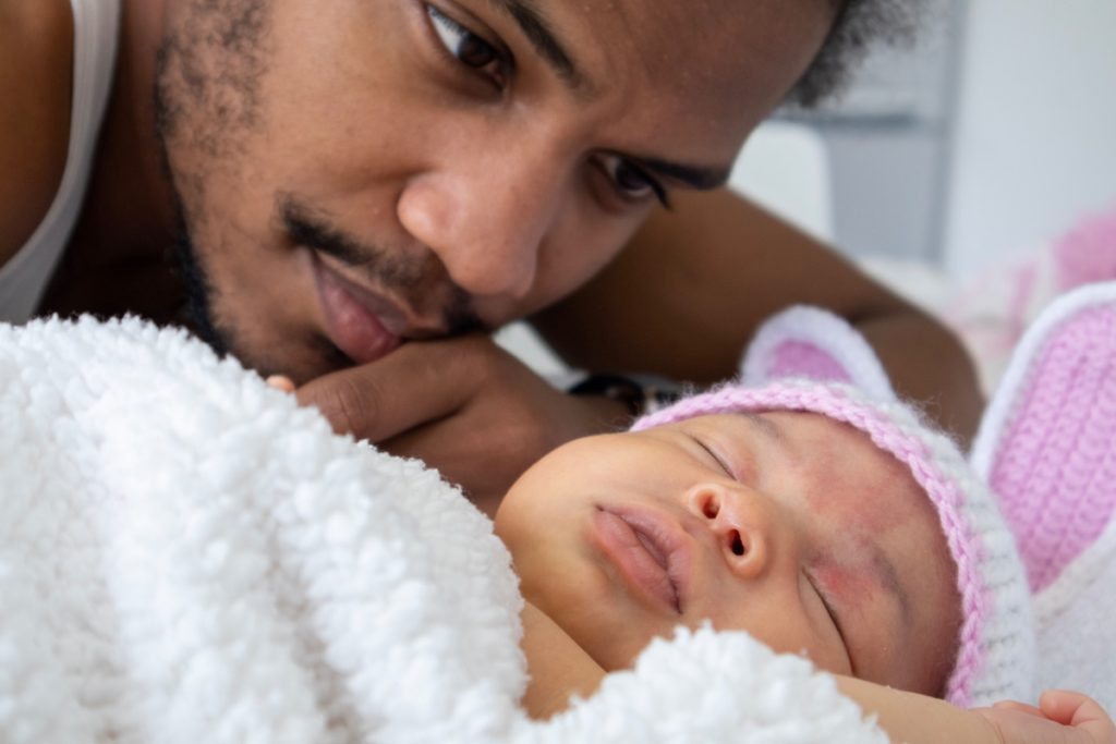 Un hombre mira a un bebé que duerme - Fuente: Unsplash